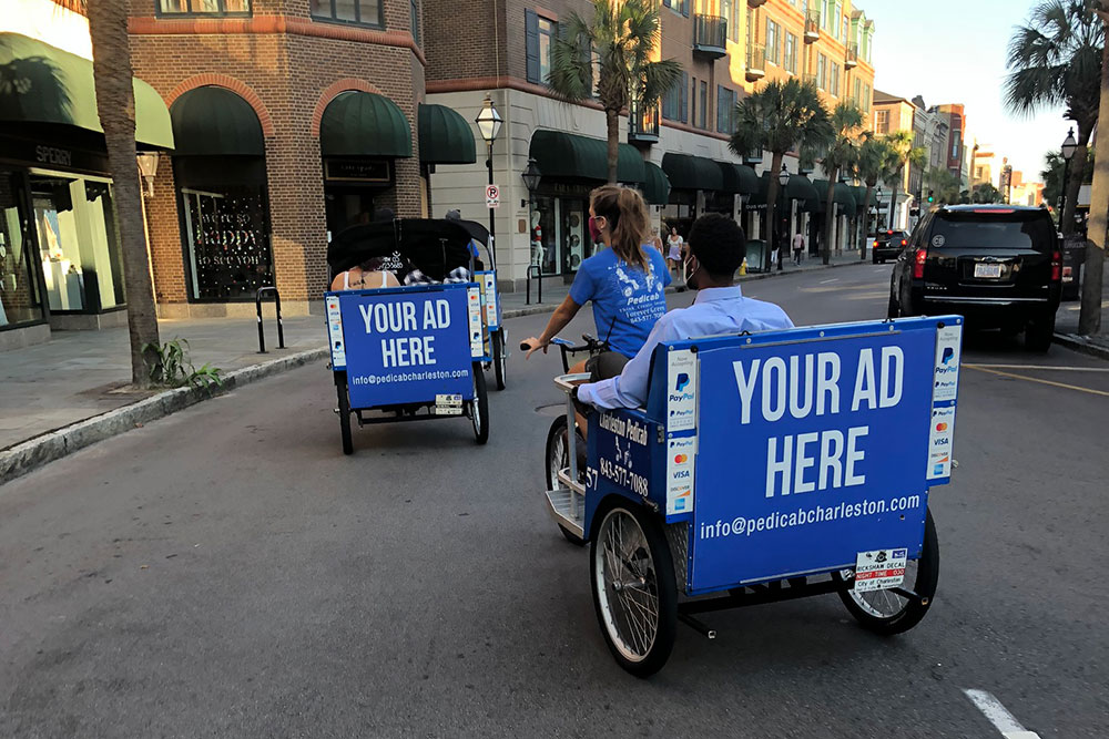 Pedicabs with "Your Ad Here" signs on the back in Downtown Charleston